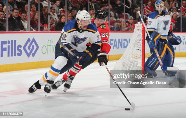 Justin Faulk of the St. Louis Blues is defended by Sam Lafferty of the Chicago Blackhawks at United Center on November 16, 2022 in Chicago, Illinois.