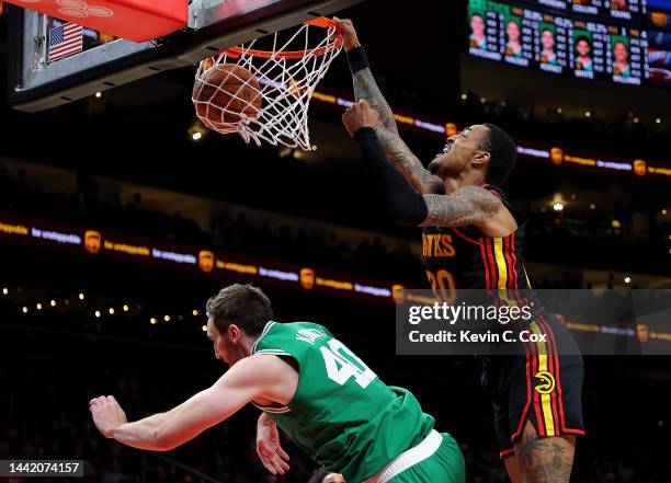 John Collins of the Atlanta Hawks dunks over Luke Kornet of the Boston Celtics during the second half at State Farm Arena on November 16, 2022 in...