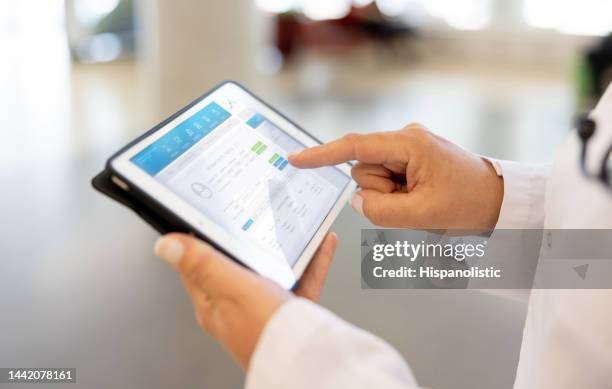 médico usando una aplicación móvil en una tableta en el hospital - informe-médico fotografías e imágenes de stock