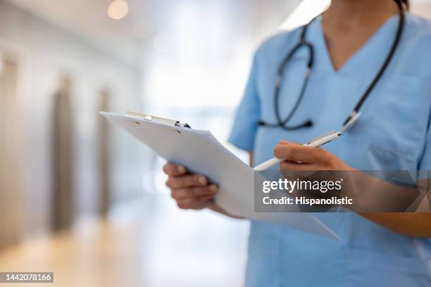 primer plano de una enfermera escribiendo en una historia clínica en el hospital - tablilla con sujetapapeles fotografías e imágenes de stock