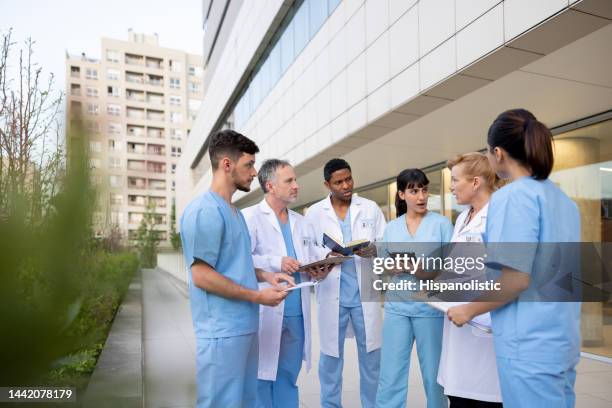 grupo de trabajadores de la salud hablando fuera del hospital - resident fotografías e imágenes de stock