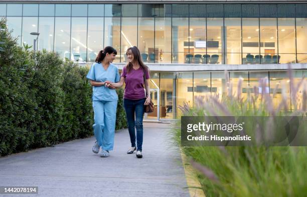 krankenschwester hilft einem patienten bei der remission beim verlassen des krankenhauses - doctors walking stock-fotos und bilder
