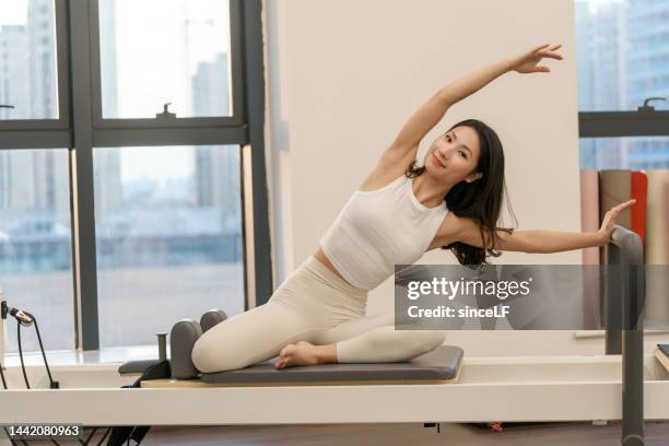 pilateslehrerin im weißen yogaanzug, schöne junge asiatin - pilates gerät stock-fotos und bilder