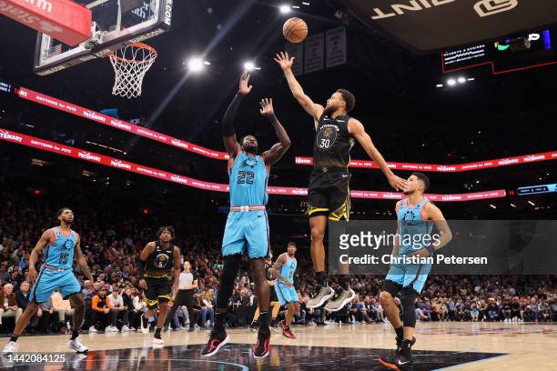 Stephen Curry of the Golden State Warriors puts up a shot over Deandre Ayton of the Phoenix Suns during the first half of the NBA game at Footprint...