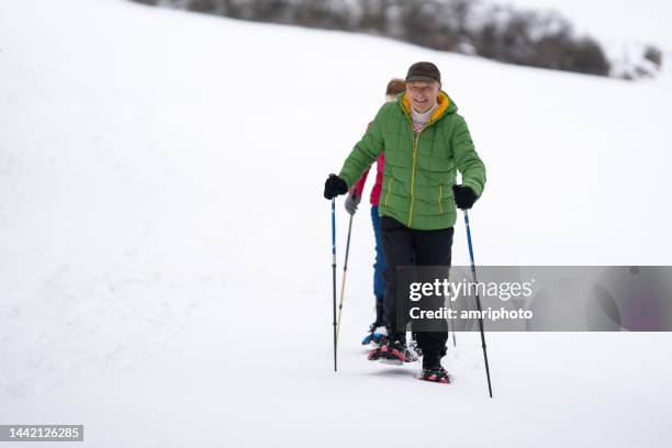 smiling senior man snowshoe walking with his wife - senior winter sport stock pictures, royalty-free photos & images