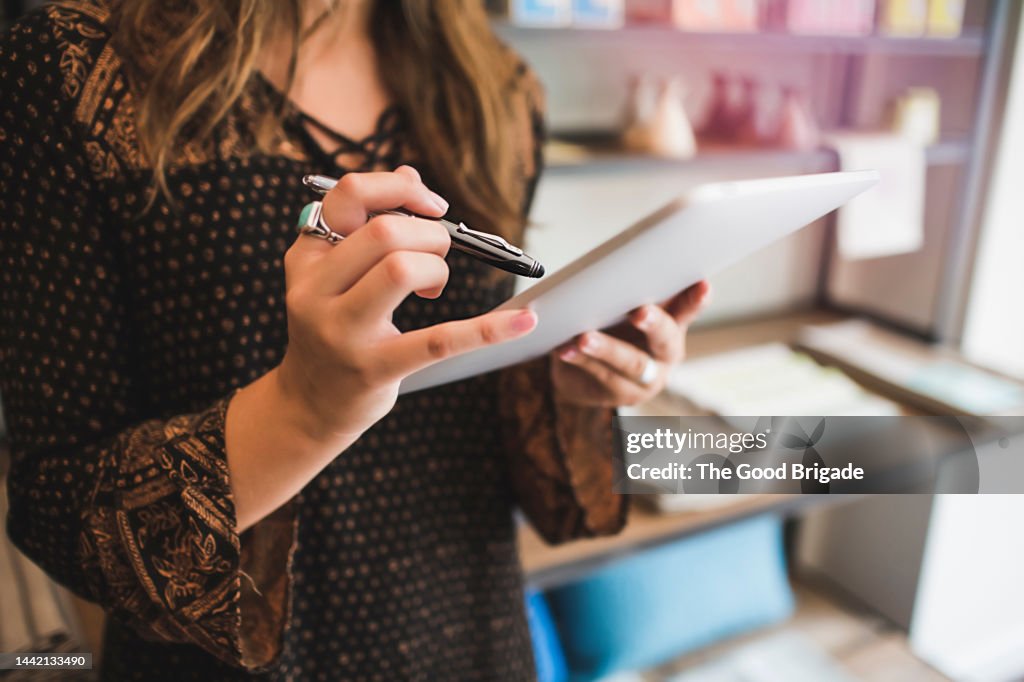 Close up of female shop owner using digital tablet