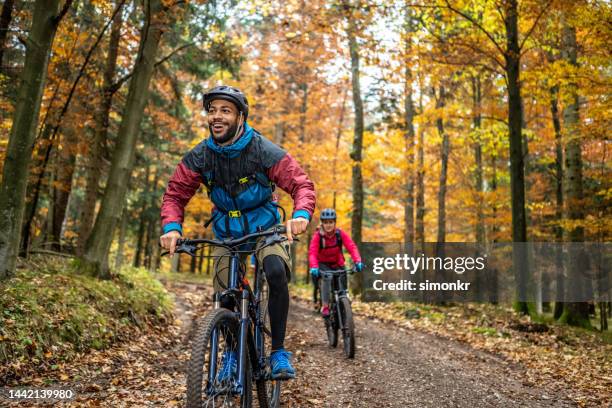 hombre y mujer montando bicicletas de montaña en el bosque - mountain biking fotografías e imágenes de stock