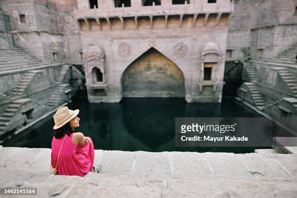 rear view of cute tourist girl sitting at a step well - jodhpur imagens e fotografias de stock