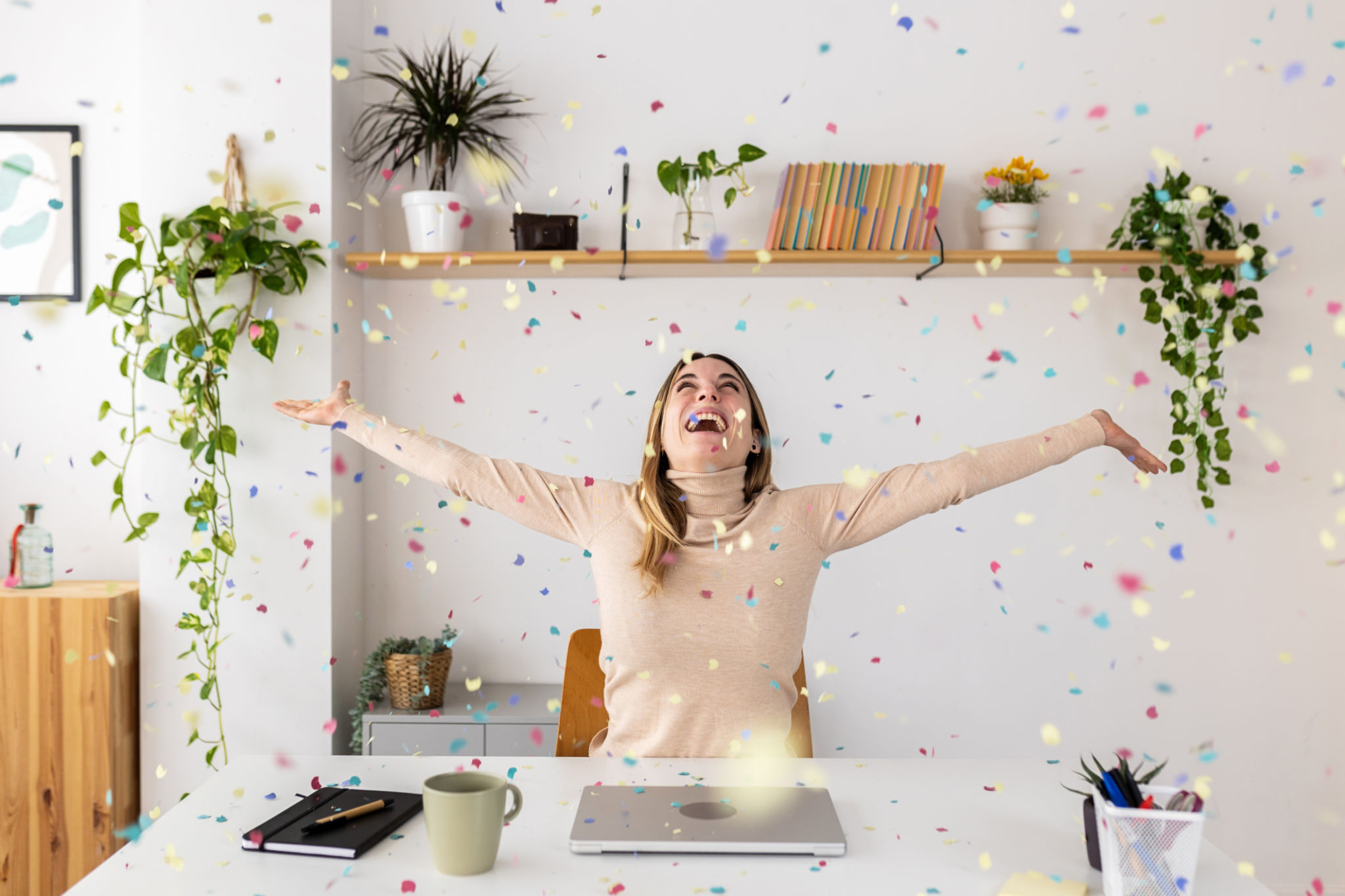 Young businesswoman celebrating success throwing confetti sitting at home office Young businesswoman celebrating success throwing confetti sitting at home office