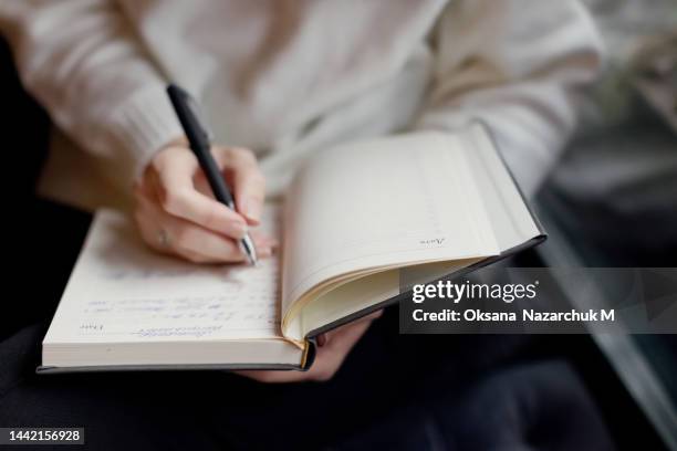 caucasian woman writing in notebook indoors - agenda imagens e fotografias de stock