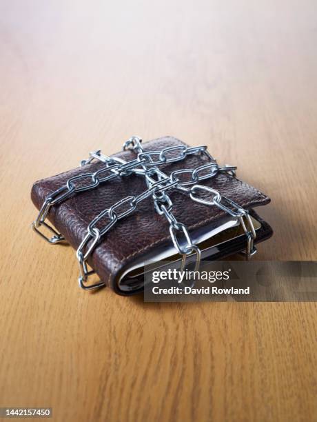 a leather wallet on a table top wrapped in chain - 緊縮財政 ストックフォトと画像