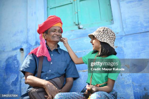 affectionate granddaughter touching her grandfather cheeks wearing a traditional red turban - indian family vacation stock pictures, royalty-free photos & images