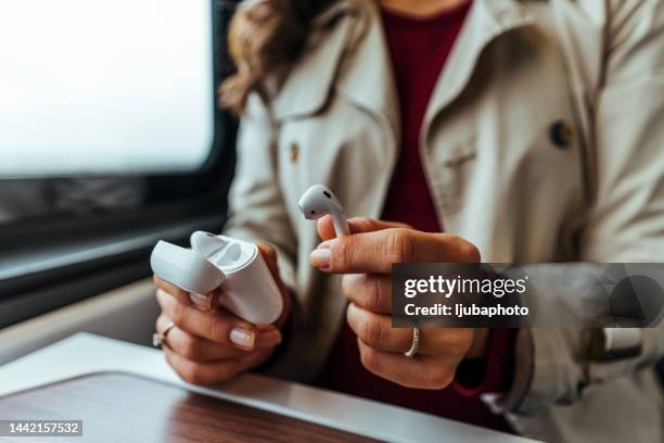close-up of a woman taking out a white wireless earbud from his charging box. - wireless in ear headphones stock pictures, royalty-free photos & images