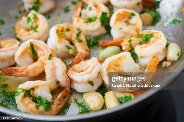 hand mixing shrimp food with parsley on pan. keto meal fried prawn for ketogenic diet, preparing sauce for pasta, seafood prawn sizzling in metal frying pan, hot pan-fried paleo food with crispy crust of food rich in cholesterol - shrimp animal stock pictures, royalty-free photos & images