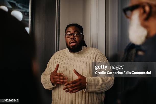 a man is animated as he uses hand gestures and talks to onlookers - bestimmtheit stock-fotos und bilder