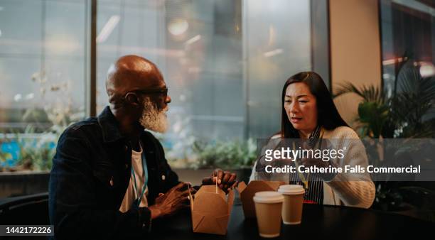 two colleagues have a discussion while eating a takeaway lunch - breakfast close stock pictures, royalty-free photos & images