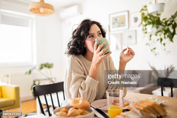 mujer joven desayunando en casa tomando café - café bebida fotografías e imágenes de stock