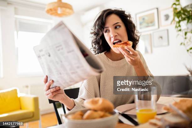 young woman having breakfast at home reading newspaper - newspaper on table stock pictures, royalty-free photos & images