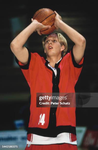 German basketball player Dirk Nowitzki wearing a headband and a red shirt with black trim, holding a basketball at DJK Wurzburg, in Wurzburg,...