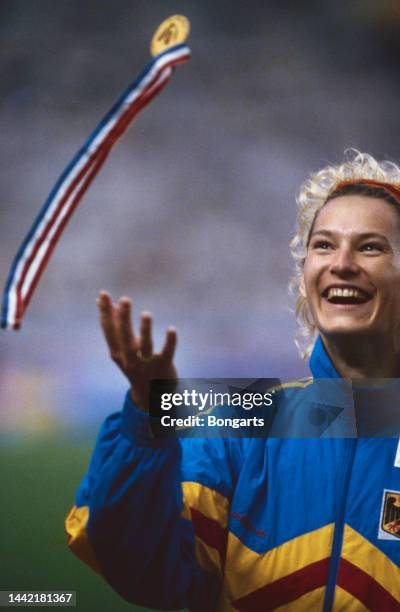 German athlete Heike Drechsler smiles as she throws her gold medal in the air after receiving the medal for winning the women's long jump event at...