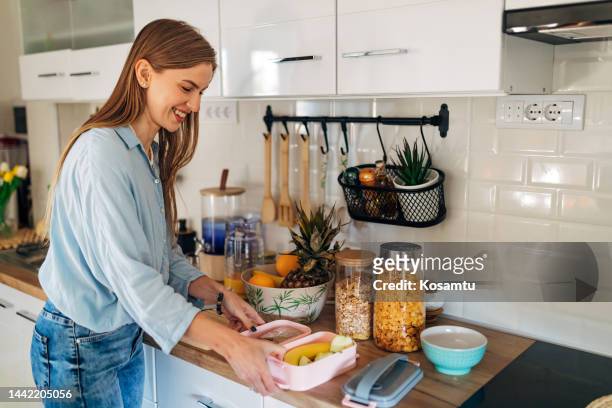 cheerful woman packs lunch in a lunch box for her daughter who goes to school - packed lunch stock pictures, royalty-free photos & images