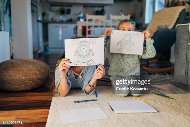 front view of mother and daughter in living room showing drawings directly to camera - monster stock pictures, royalty-free photos & images