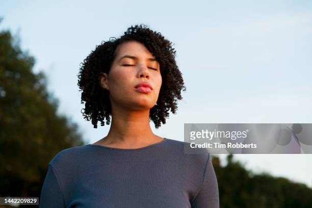 woman with eyes closed at dusk - atemübung yoga 30 bis 40 jahre stock-fotos und bilder