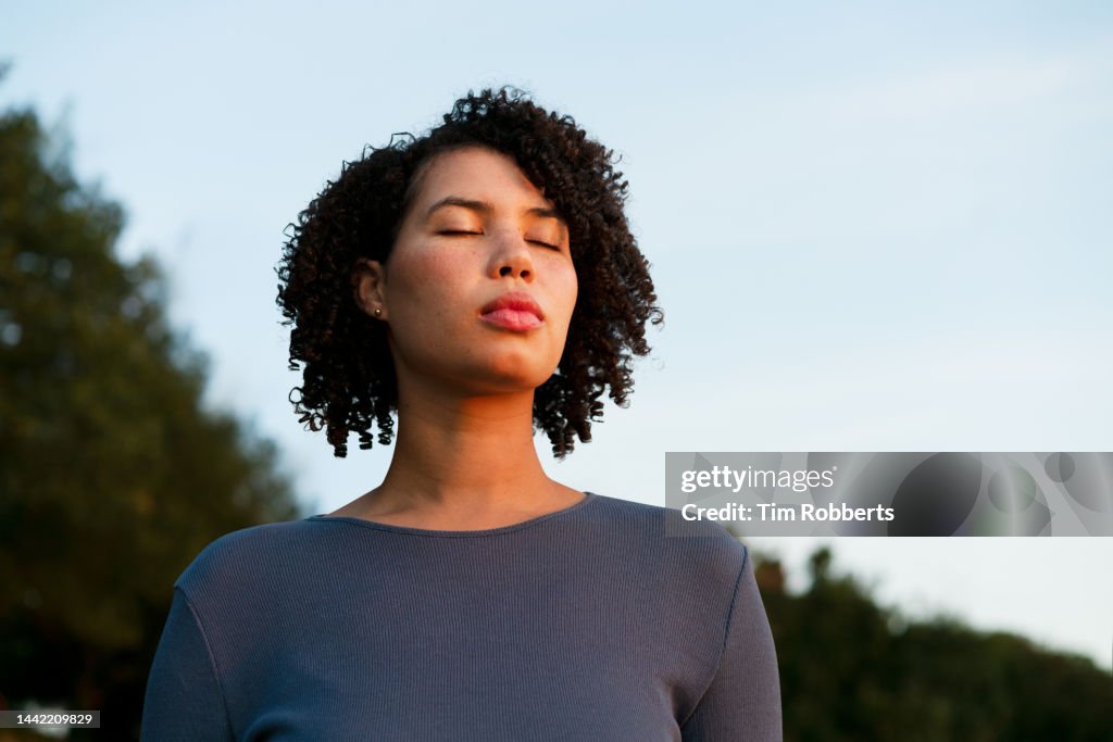 Woman with eyes closed at dusk