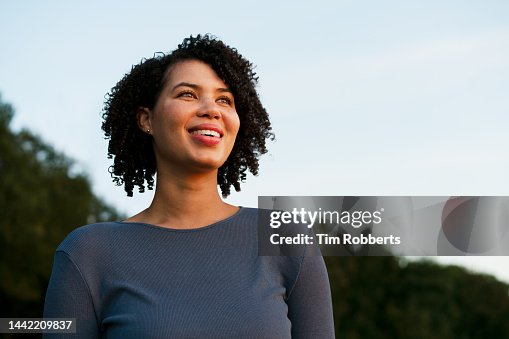 Woman smiling, looking up, dusk Woman smiling, looking up, dusk