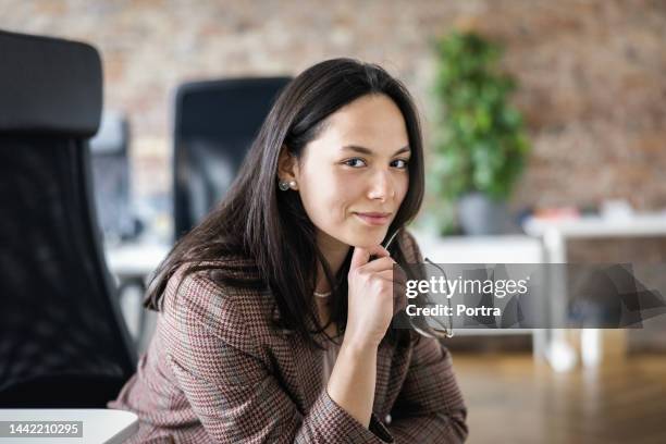 portrait of a confident young businesswoman working at her desk in office - managing director 個照片及圖片檔