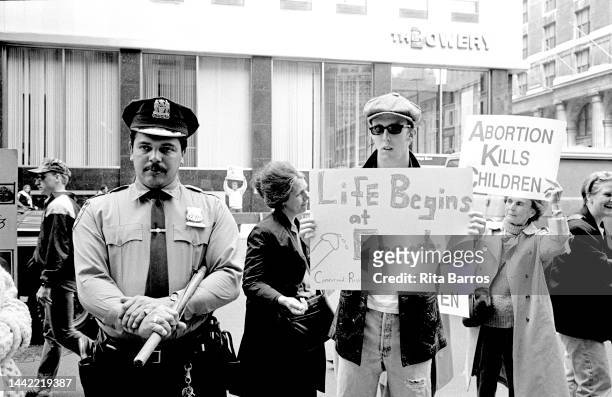 As a police officer stands by, an activist holds a sign that reads 'Life Begins at Erection' during an anti-abortion march along Fifth Avenue, New...