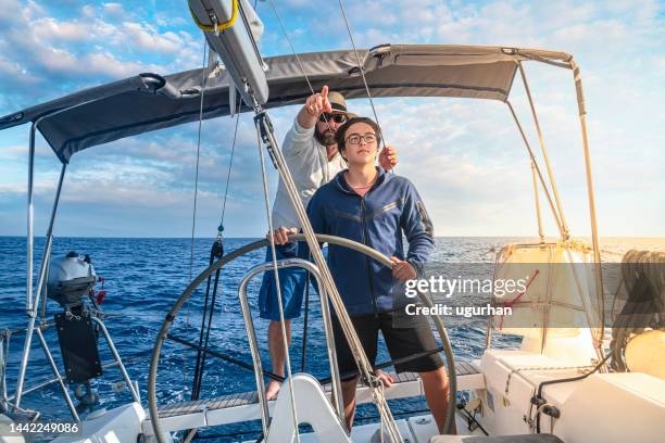 ein vater bringt seinem sohn das segelboot bei und führt ihn. - father son sailing stock-fotos und bilder