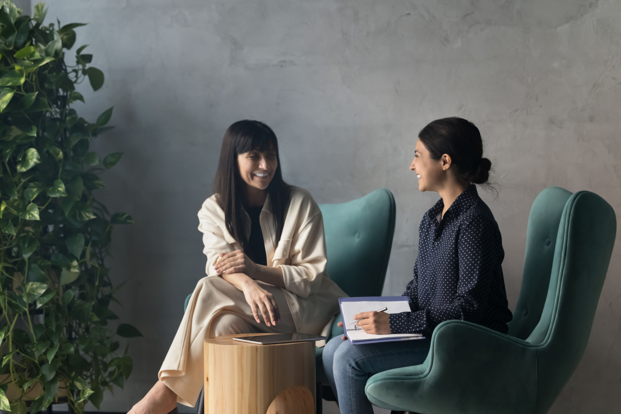 Two businesswomen laughing during meeting in modern cozy office lobby Two businesswomen laughing during meeting in modern cozy office lobby