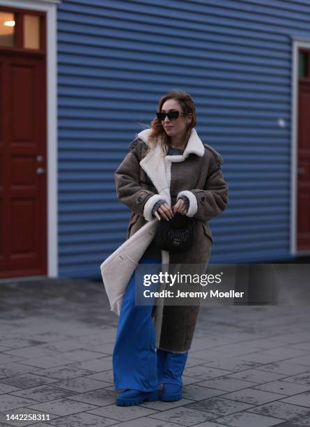 Sonia Lyson is seen wearing Copenhagen Studios CPH149 recycled nylon royal blue boots, black Miu Miu sunglasses, H&M blue wide leg jogging pants,...