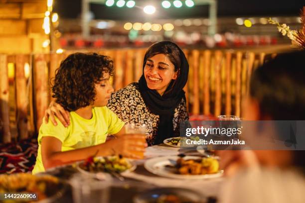 middle eastern mother smiling at her son at dinner in dubai - middle eastern food stockfoto's en -beelden