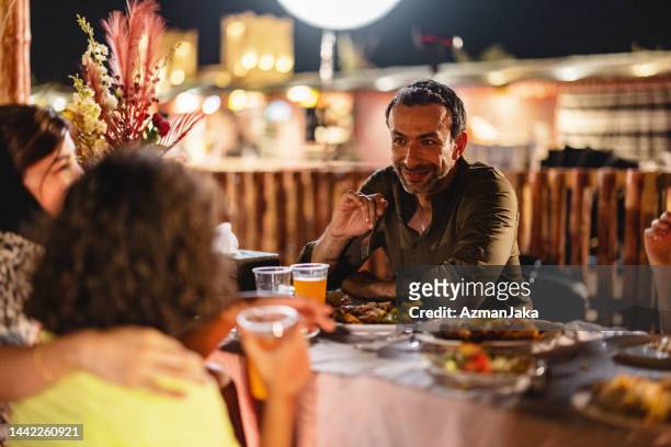 un père du moyen-orient parle avec la famille lors d’un dîner à dubaï - arabian desert adventure night photos et images de collection