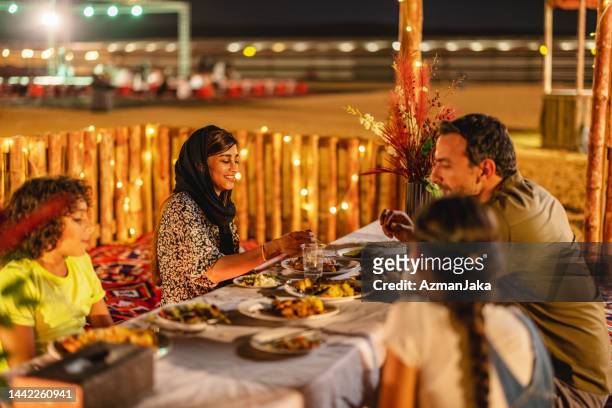 famille mangeant de la nourriture arabe dans un camp du désert à dubaï - arabian desert adventure night photos et images de collection