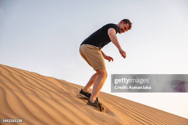 portrait of a tourist experiencing sandboarding  in dubai - sand boarding stock pictures, royalty-free photos & images