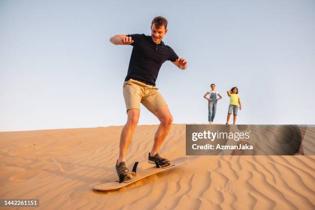 tourist man sandboarding in dubai - sandboarding stock pictures, royalty-free photos & images