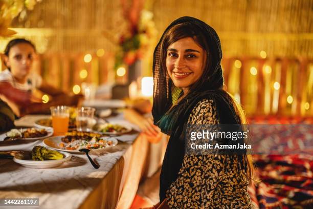 portrait d’une mère du moyen-orient souriant à la caméra lors d’un dîner à dubaï - arabian desert adventure night photos et images de collection