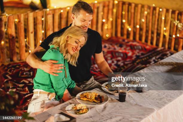 un couple de caucasiens s’étreignant lors d’un dîner dans un camp du désert la nuit à dubaï - arabian desert adventure night photos et images de collection