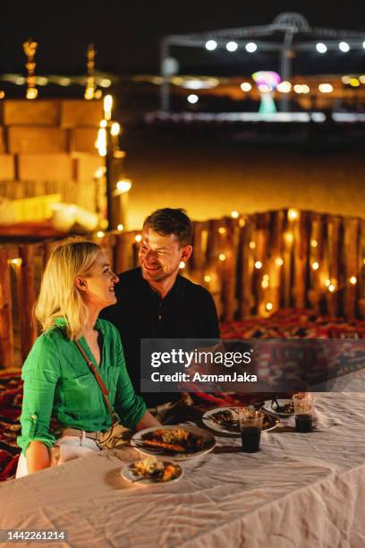 adult female tourist looking at the camera at dinner in a safari camp in dubai - arabian desert adventure night stock pictures, royalty-free photos & images