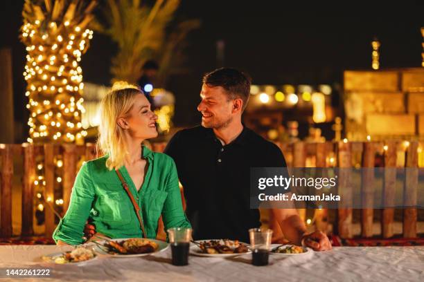 adult female tourist looking at the camera at dinner in a safari camp in dubai - arabian desert adventure night stock pictures, royalty-free photos & images