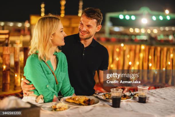 beau couple de caucasiens dînant dans un camp de safari la nuit à dubaï - arabian desert adventure night photos et images de collection