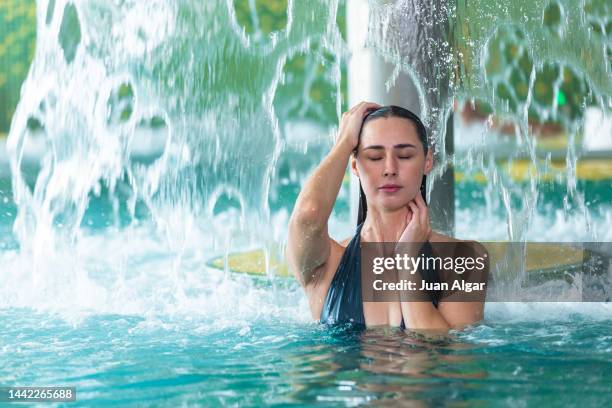 woman swimming in pool under waterfall with splashing water - algar waterfall spain stock pictures, royalty-free photos & images