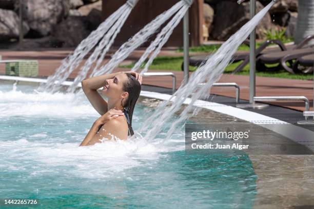 happy woman in pool under massage shower - algar waterfall spain stock pictures, royalty-free photos & images