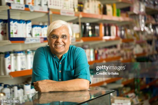 smiling owner standing at checkout in store - indian shopkeeper stock pictures, royalty-free photos & images