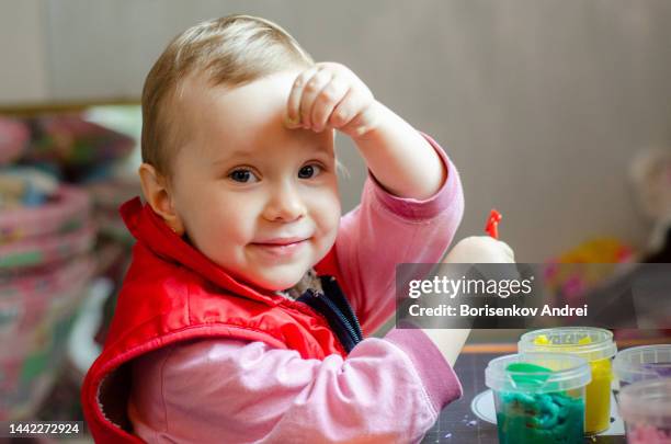 a child, caucasian, 3 years old, enthusiastically sculpts from plasticine, he rejoices and smiles, looks into the photo camera - 2 3 years stockfoto's en -beelden