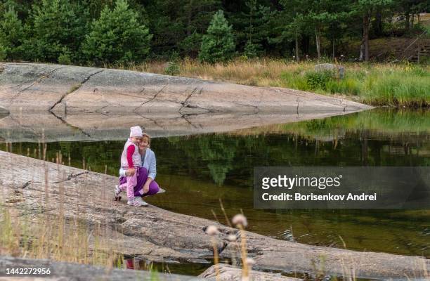 a young woman with a 4-year-old child stands on a rocky shore of a bay far from the city. the family enjoys silence away from the bustle of the city. - baltic sea stock pictures, royalty-free photos & images