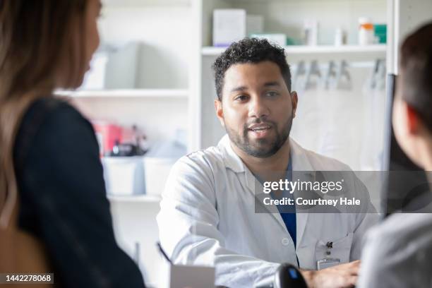 mid adult pharmacist explaining medication to a mother and her son. - pharmacist and patient imagens e fotografias de stock